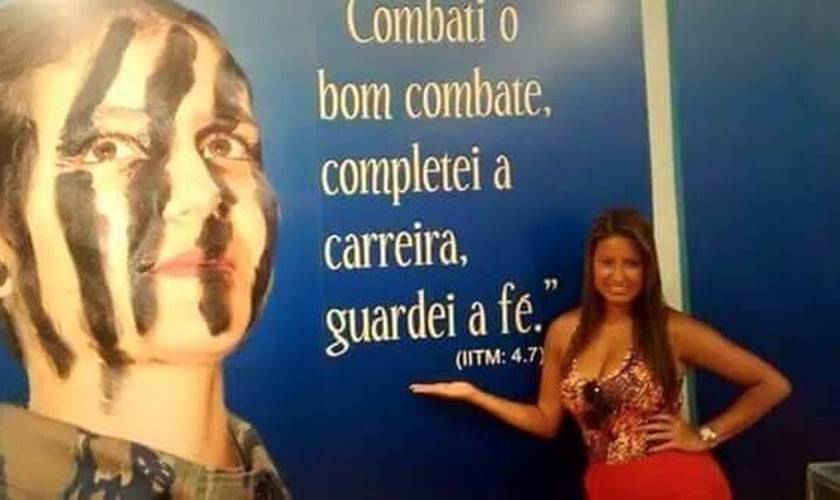 Drielle diante de mural com versículo: "Combati o bom combate, completei a carreira, guardei a fé". (Jornal Atual Rio)