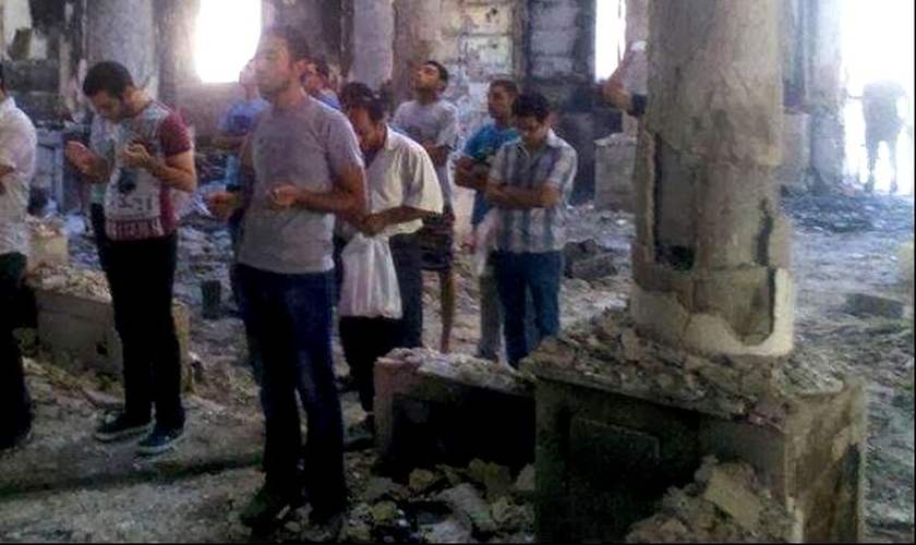 Cristãos oram dentro de templo em ruínas, na Síria.
