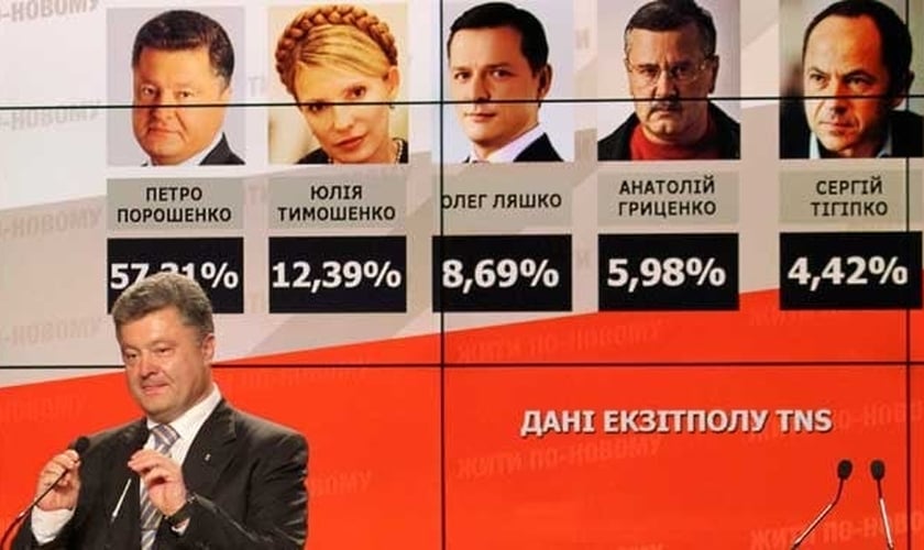 Empresário Petro Poroshenko fala para simpatizantes em frente a um quadro com resultados boca de urna que já o indicavam como novo presidente da Ucrânia