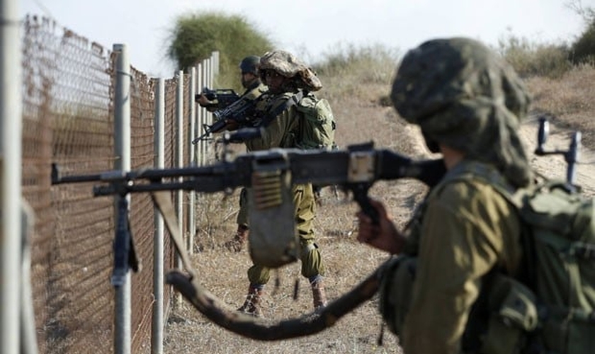 Soldados israelenses se posicionam ao lado de cerca na cidade de Sderot durante infiltração de militantes palestinos nesta segunda-feira (21) 