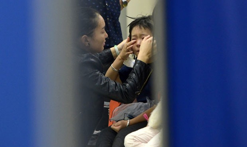 Mulher atende criança da escola Mingtong, onde seis alunos morreram durante um tumulto nesta sexta-feira