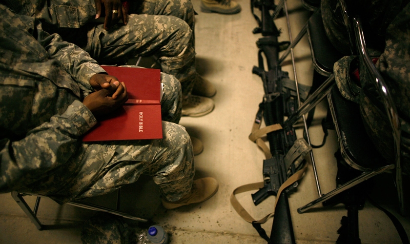 Soldado com a Bíblia Sagrada no colo durante reunião. (Foto: Associated Press)