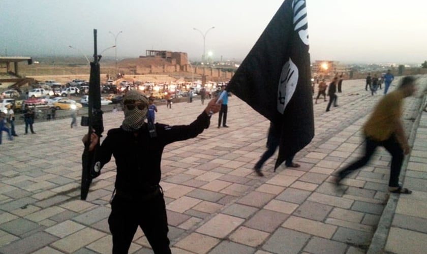 Militante do Estado Islâmico levanta bandeira do grupo terrorista no Iraque, país onde as casas de cristãos foram marcadas com o mesmo sinal correspondente à letra 'N' do alfabeto ocidental, como sigla para a palavra "nazareno" (Foto: Reuters)