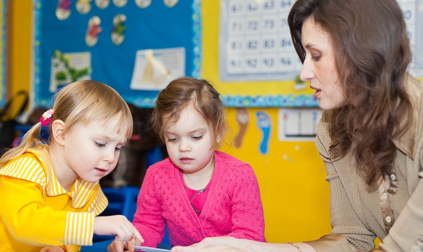 Professora ajuda crianças em sala de aula (Imagem: Istok)