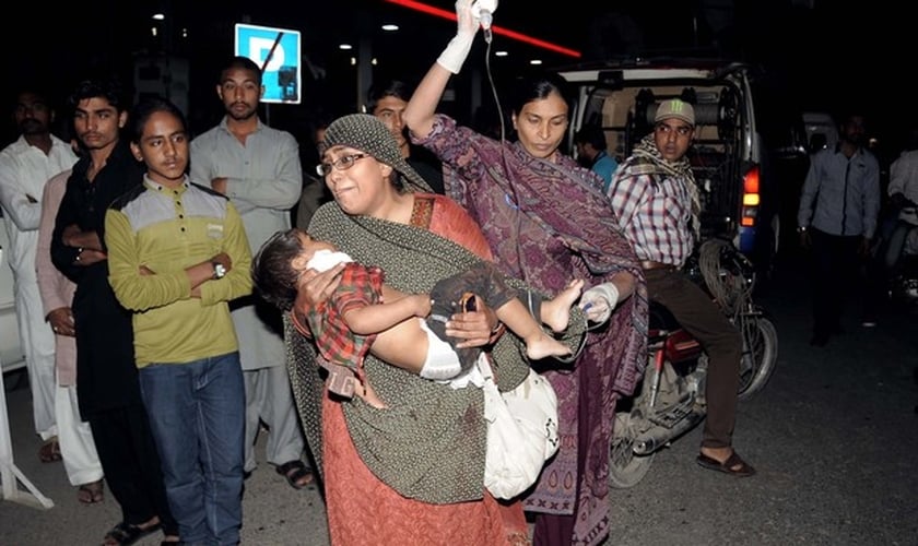 Mulher segura criança que ficou ferida em atentado em parque de Lahore. (Foto: Arif Ali/AFP)