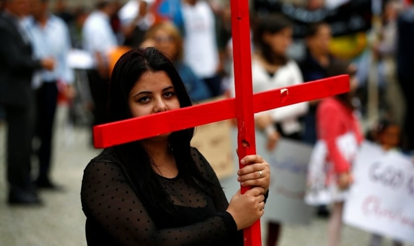 Mulher segura uma cruz durante protesto organizado por cristãos iraquianos na Alemanha. (Foto: Reuters / Thomas Peter)