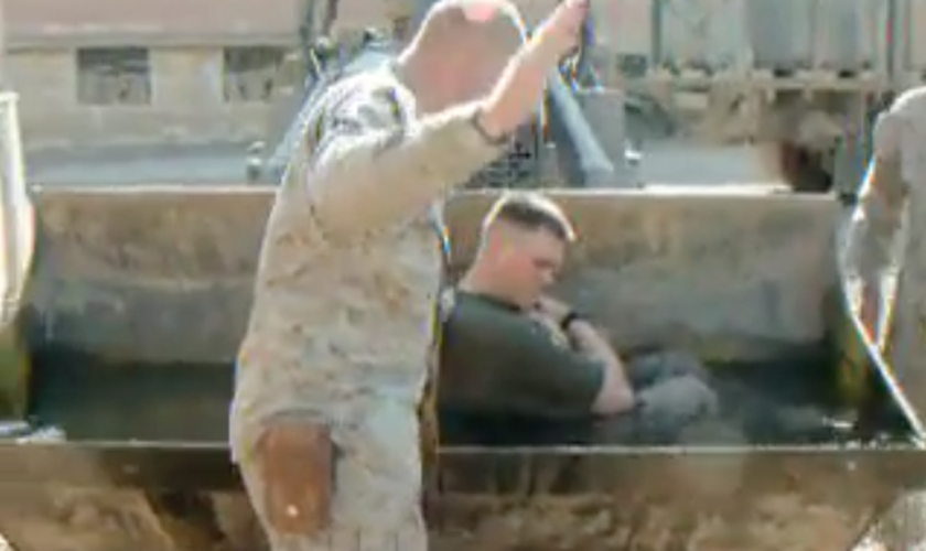Soldado dos EUA é batizado no carregador frontal de um trator, no Iraque. (Foto: Reprodução/Facebook)