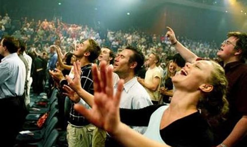 Pessoas participam de animado momento do culto na igreja.