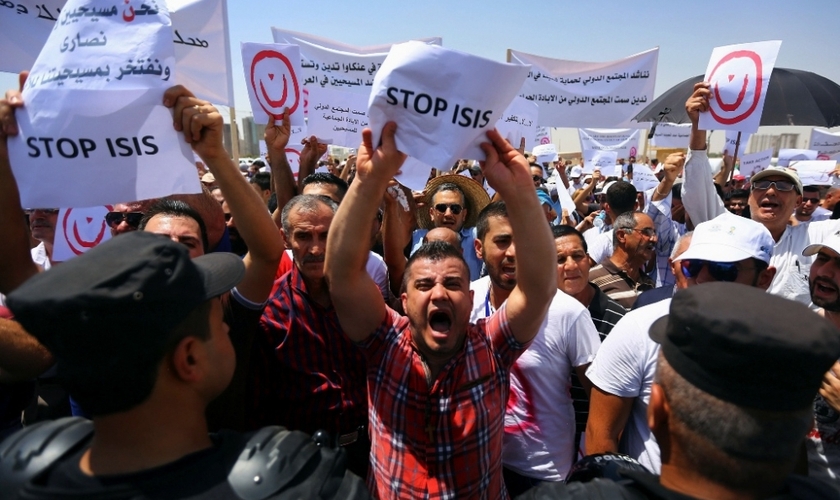 Manifestantes seguram placas e cartazes em protesto contra o Estado Islâmico no Iraque. (Foto: Reuters)