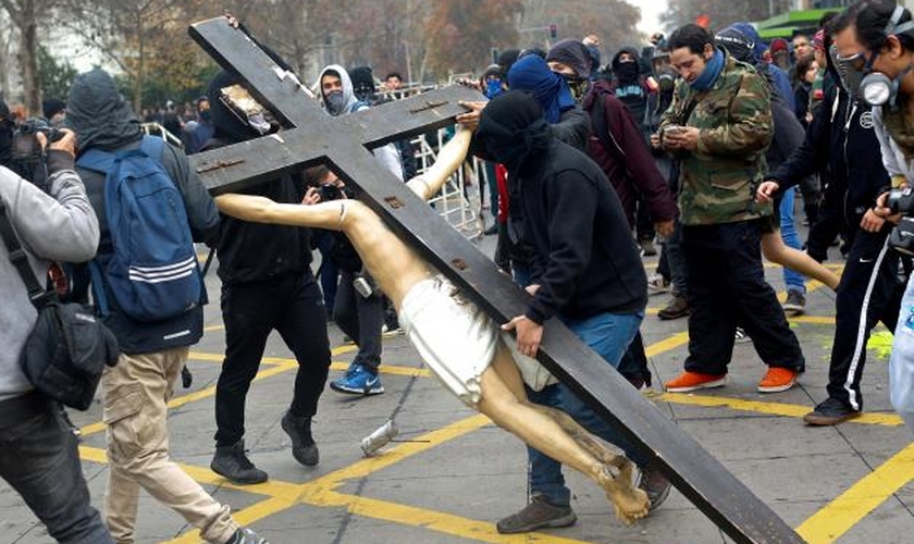 Ao final da marcha, da última quinta-feira, manifestantes mascarados entraram em uma igreja no centro de Santiago e destruíram a cruz 3 de metros de altura, com uma estátua de Jesus Cristo. (Foto: Reuters)