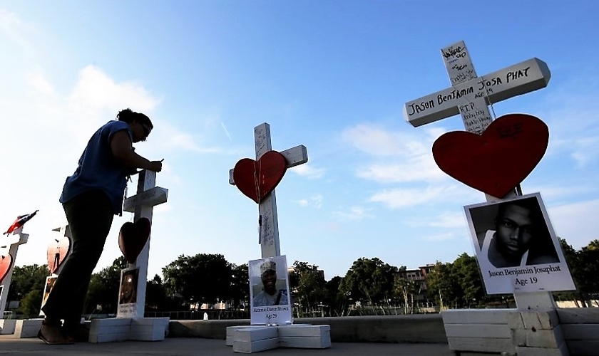 Mulher escreve uma mensagem em uma cruz em honra daqueles que foram mortos na boate gay 'Pulse', em Orlando. (Foto: Reuters)