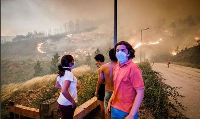 Pessoas assistem de longe às chamas se espalhando pela mata, na região de Pedrógão Grande. (Foto: Global Imagens)