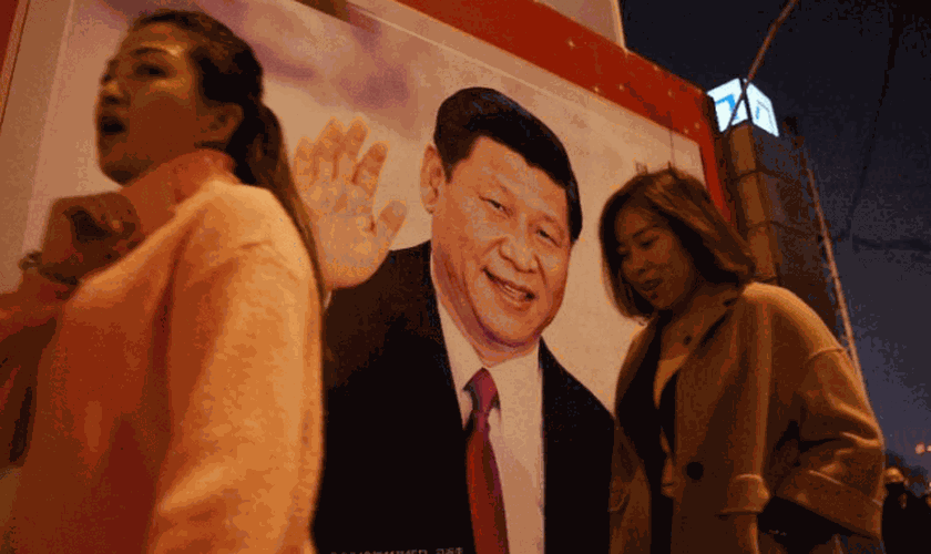 Pessoas passam por foto do presidente Xi-Jinping, exposta em rua da China. (Foto: Breitbart)