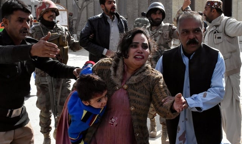 Policial conduz uma família depois que homens armados atacaram uma igreja protestante no Paquistão. (Foto: Reuters)