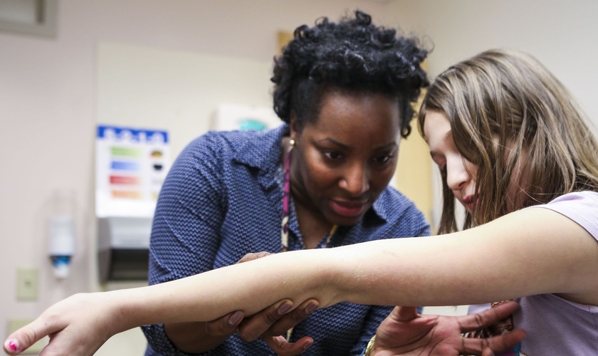 Médica analisa braço de criança na clínica transgênero de Cincinatti, nos Estados Unidos. (Foto: Cincinnati Enquirer)