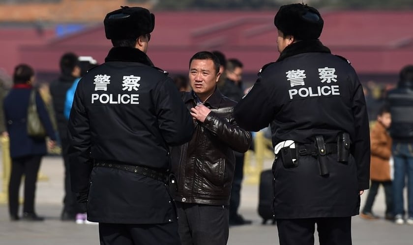 Policiais interrogam um homem na Praça Tiananmen, em Pequim. (Foto: Greg Baker/Agence France-Presse — Getty Images)