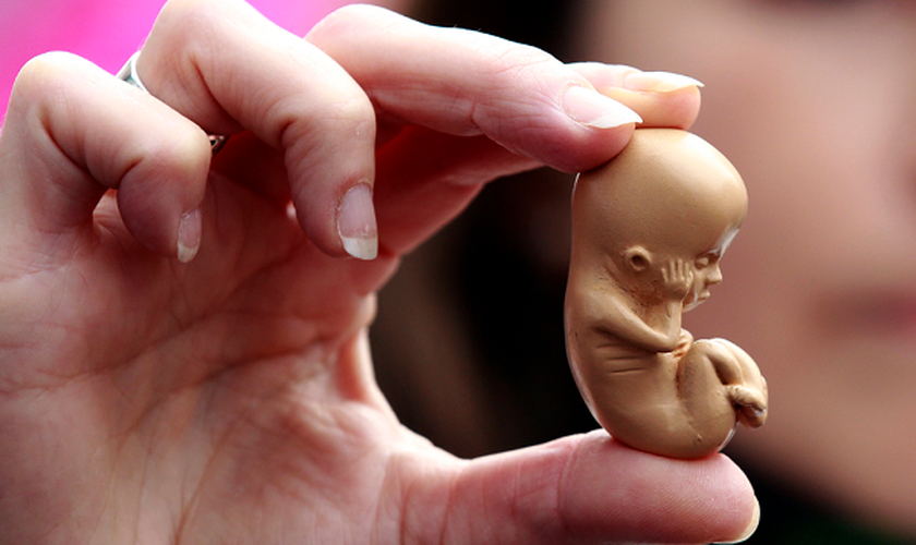 Ativista pró-vida segura um modelo de embrião durante protesto em Belfast. (Foto: Cathal Mcnaughton/Reuters)