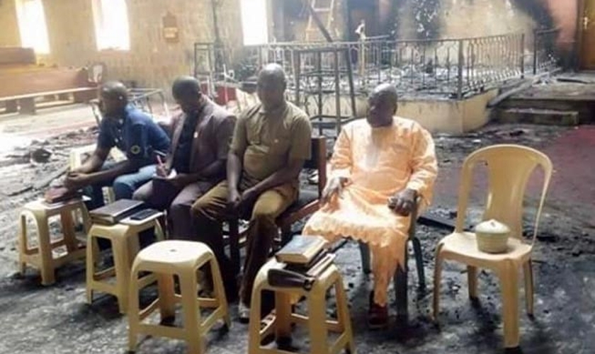 Os anciãos da igreja nigeriana realizam o culto de domingo em meio às cinzas de sua igreja incendiada apenas dois dias após um devastador ataque ao Boko Haram. (Foto: Reprodução / Barnabas)