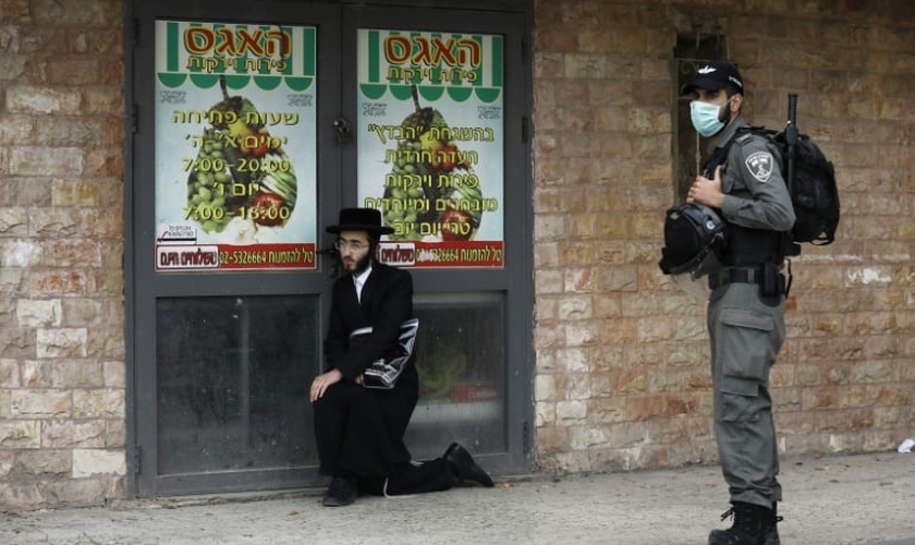 Policial israelense detém um judeu ultraortodoxo durante patrulha em Jerusalém. (Foto: Reprodução/AFP)
