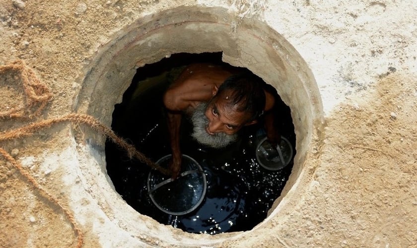 Jamshed Eric trabalhando em um esgoto em Karachi no ano passado. (Foto: Reprodução/NYT)