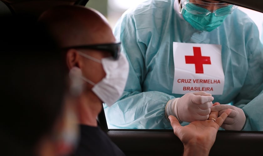 Funcionária da Cruz Vermelha realiza teste drive-thru de coronavírus em Brasília. (Foto: Ueslei Marcelino/Reuters)