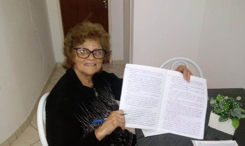 Maria Petrina exibe um dos cadernos com cópias da Bíblia. (Foto: Reprodução)