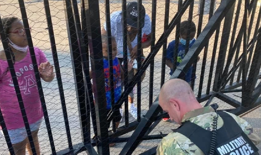 O soldado Dan Otterson (de farda) se ajoelhou, enquanto o garoto de 5 anos orou por ele, do outro lado da cerca. (Foto: Facebook)