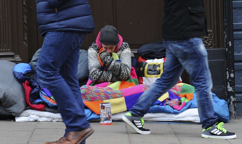 Pedestres passam por um morador de rua no Reino Unido. (Foto: Daniel Sorabji/AFP)