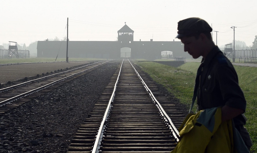 Homem atravessa trilhos do antigo campo de concentração de Auschwitz, na Polônia. (Foto: AP/Alik Keplicz)