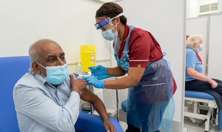 O trabalhador de uma casa de repouso, Pillary Jagambrun, de 61 anos, recebe dose da vacina da Pfizer-BioNTech contra de Covid-19 no Hospital da Universidade Croydon, no sul de Londres, na terça-feira. (Foto: PA)