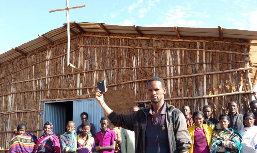 Em frente à igreja na África, cristãos seguram aparelho da Bíblia em áudio. (Foto: GHI)