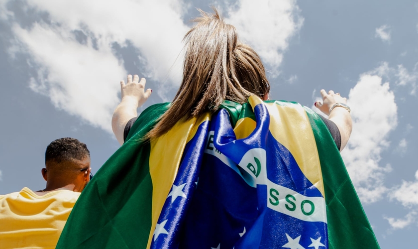 Jovem com bandeira do Brasil em momento de oração, em 8 de fevereiro de 2020. (Foto: The Send Brasil)