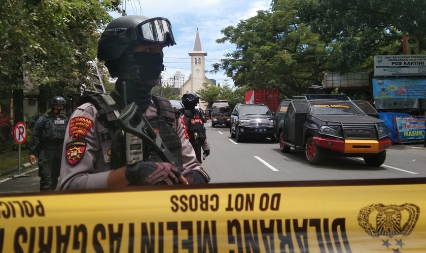 Policiais montam guarda ao longo de uma rua fechada após explosão em frente a igreja, na Indonésia. (Foto: Antara Foto/Arnas Padda via Reuters)