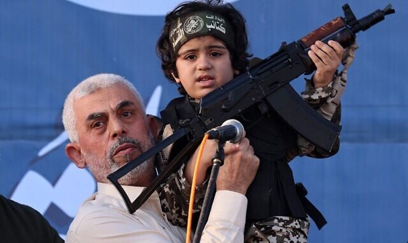 Líder do Hamas, Yahya Sinwar, segura o filho de um membro que foi morto no confronto com Israel. (Foto: Emmanuel Dunand/AFP)