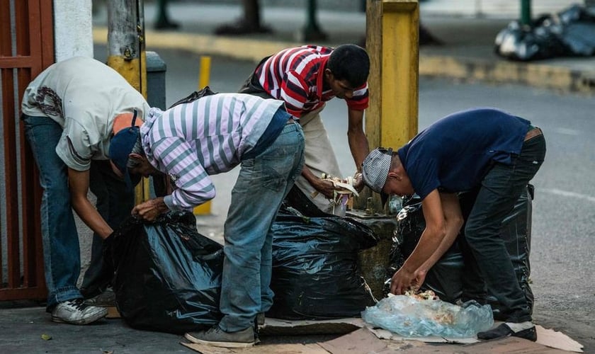 Pessoas vasculham lixo em busca de comida nas ruas de Caracas. (Foto: Getty Images)