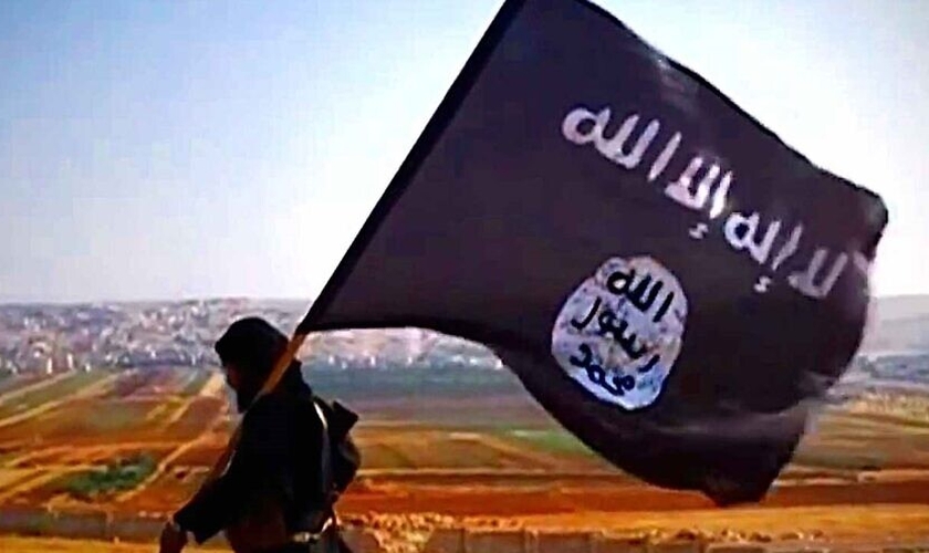 Terrorista com a bandeira do Estado Islâmico na cidade de Dabiq, na Síria, em 2013. (Foto: Wikimedia Commons)