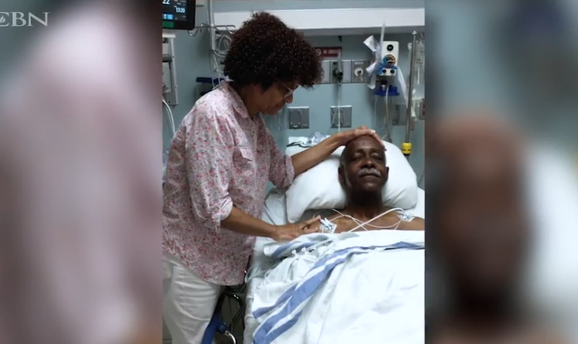Mary Johnson ora por seu marido, Robert, enquanto estava no hospital. (Captura de tela CBN News)