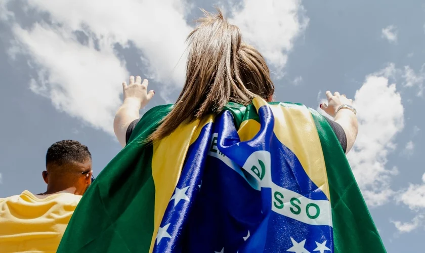 Jovem com bandeira do Brasil em momento de oração. (Foto: The Send Brasil)