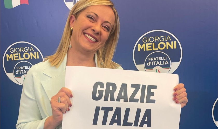 Giorgia Meloni durante discurso à imprensa, segurando placa ‘Obrigada Itália’. (Foto: Reprodução/Facebook/ Giorgia Meloni)