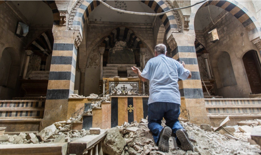 Cristão ora de joelhos em igreja destruída. (Foto: TBAW)