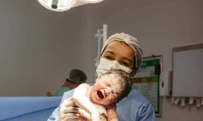 Profissional de saúde segura recém-nascido instantes após o parto. (Foto: Jonathan Borba/Unsplash)