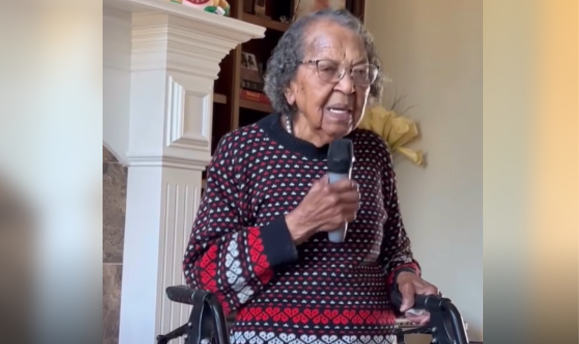 Apoiada em um andador e segurando um microfone, idosa centenária louva a Deus. (Captura de tela/Instagram/sherese.conner)