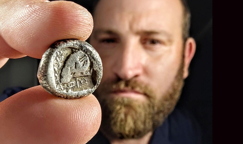 Yanniv David Levy, especialista em moedas da Autoridade de Antiguidades de Israel, segura a rara moeda de cerca de 2.500 anos. (Foto: Shai Halevi/Autoridade de Antiguidades de Israel)