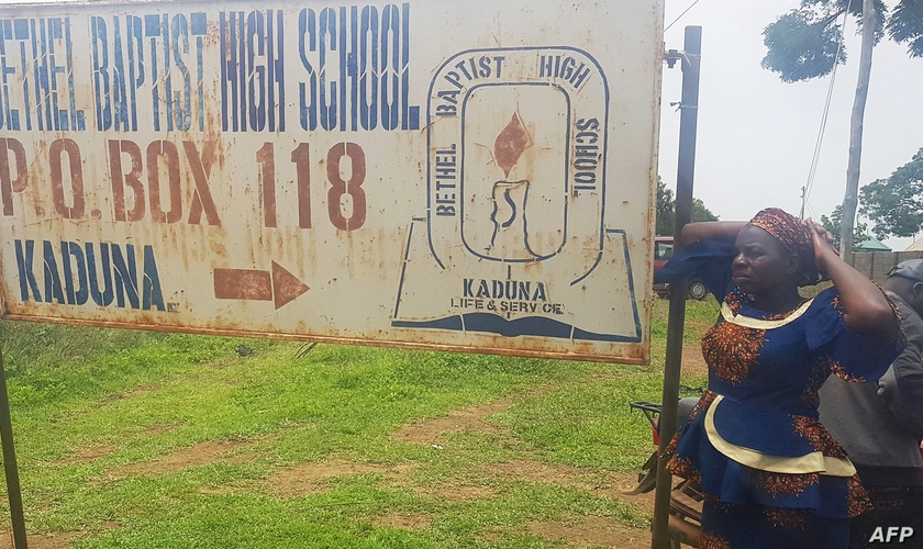 Mãe em frente a uma placa do colégio Betel Batista, em Kaduna. (Foto: Kehinde Gbenga/AFP/Getty Images)