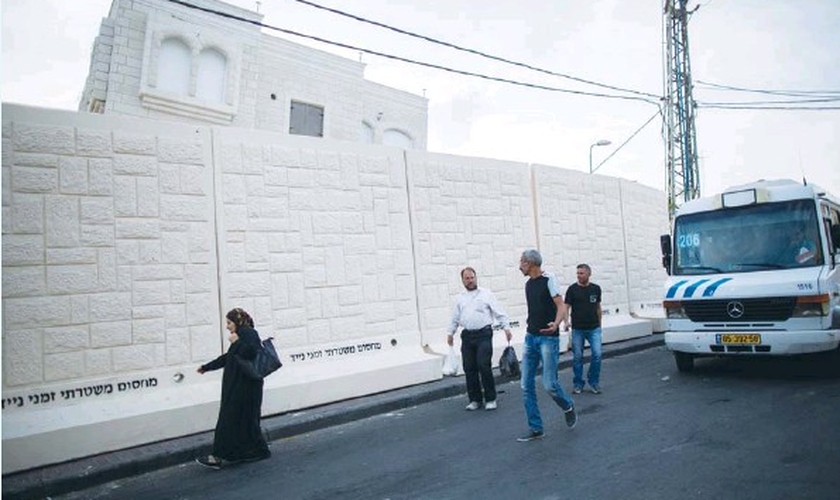 Palestinos caminham ao lado de um muro de concreto temporário no bairro Jabel Mukaber, erguido para proteger a vizinhança Armon Hanatziv de bombas e outros ataques terroristas. (Foto: Yonatan Sindel/Flash90)