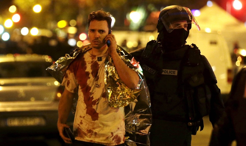 Policial acompanha vítima do ataque à casa de shows 'Bataclan', em Paris. (Foto: Reuters)
