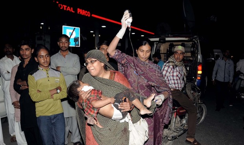 Mulher segura criança que ficou ferida em atentado em parque de Lahore. (Foto: Arif Ali/AFP)