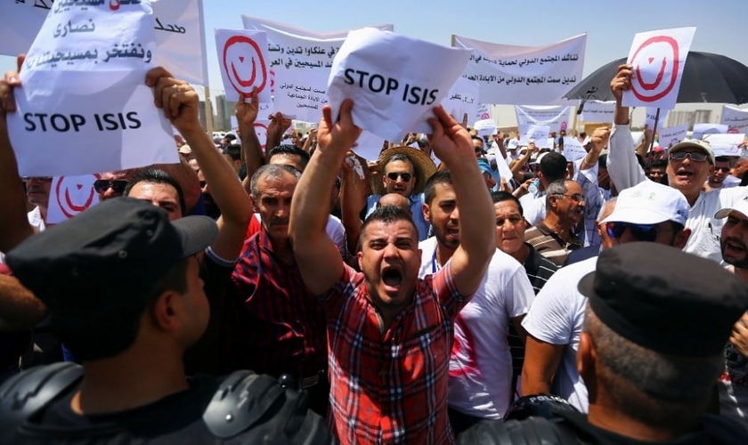Manifestantes seguram placas e cartazes em protesto contra o Estado Islâmico no Iraque. (Foto: Reuters)