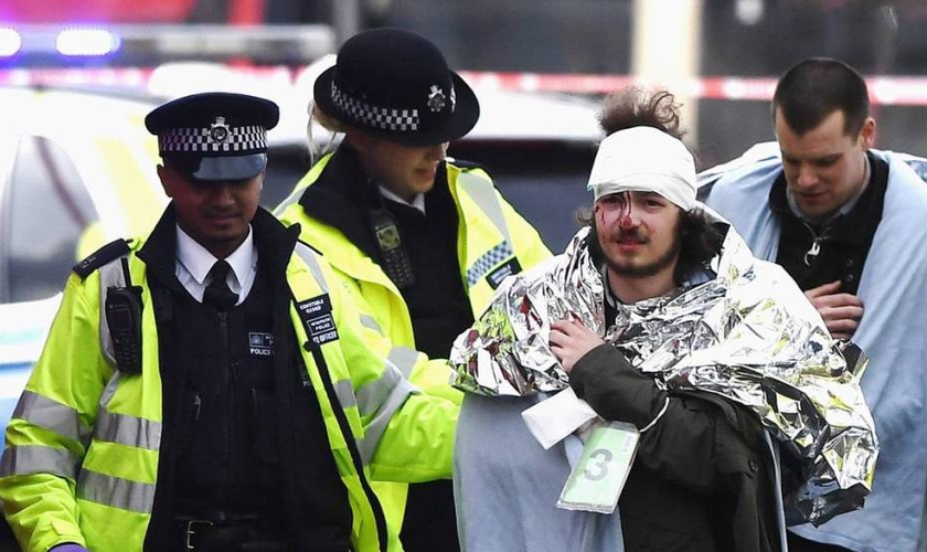 Policiais britânicos socorrem homem ferido em ataque, em Londres. (Foto: El País)