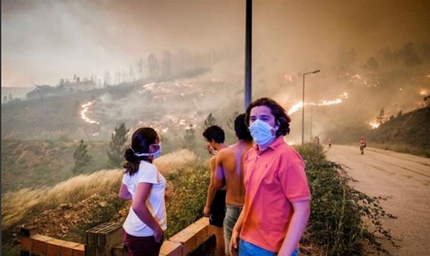 Pessoas assistem de longe às chamas se espalhando pela mata, na região de Pedrógão Grande. (Foto: Global Imagens)